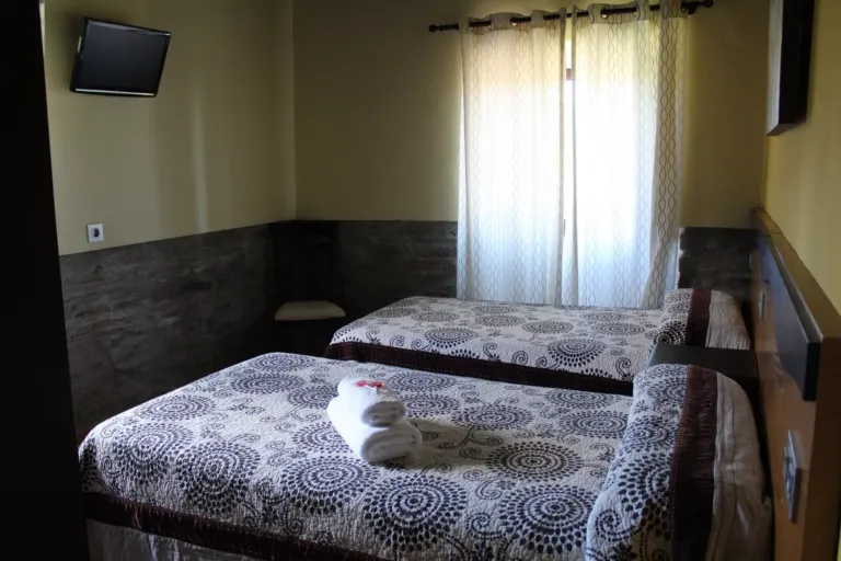 Dos camas individuales y televisión en la habitación Neftis